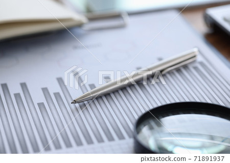 Ballpoint pen and magnifying glass lying on documents with graph in office closeup 71891937