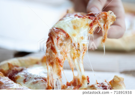 Male hand tearing off slice of pizza for lunch closeup 71891938
