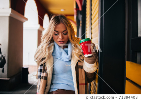 Portrait of pretty blonde girl walking in city drinking coffee 71894408