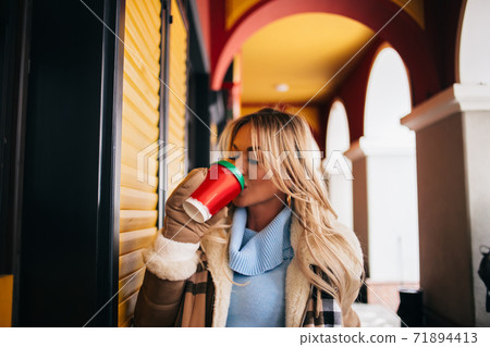 Portrait of pretty blonde girl walking in city drinking coffee Portrait of pretty blonde girl walking in city drinking coffee 71894413