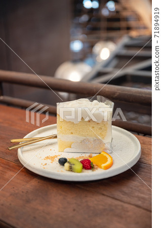 Coconut vanilla cake with whipped cream and berry fruits on plate Coconut vanilla cake with whipped cream and berry fruits on plate 71894919