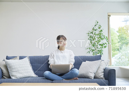 A woman using a computer in the living room 71895630