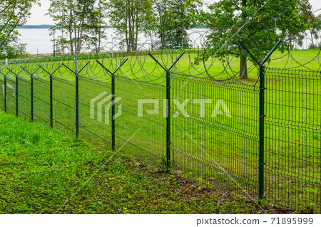 a metal fence of a military object with barbed wire 71895999