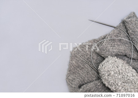 grey knitting yarn in a skein with needles and a scarf  71897016