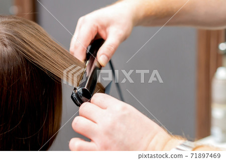 Hairdresser straightens hair of woman. 71897469