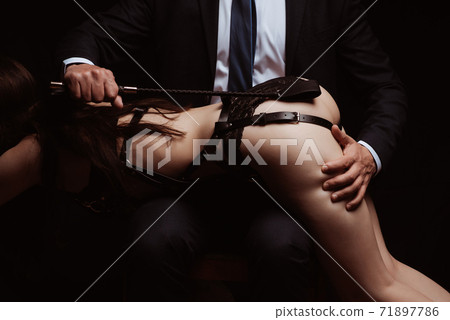 dominant man slaps a submissive girl in underwear on a sexy ass with a leather whip 71897786
