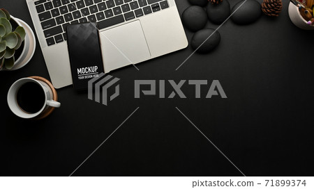 Workspace with smartphone on laptop, decorations and copy space on black table Workspace with smartphone on laptop, decorations and copy space on black table 71899374