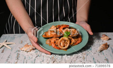 Hands holding a plate of Thai food, seafood stir-fried curry powder Hands holding a plate of Thai food, seafood stir-fried curry powder 71899378