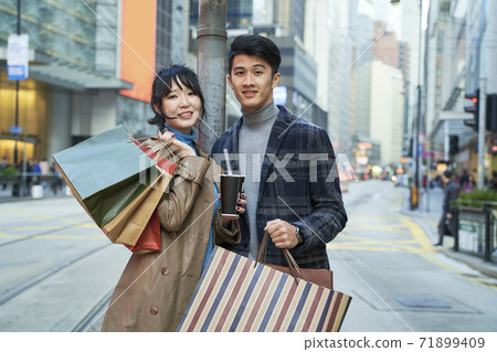 outdoor portrait of a young asian couple with shopping bags in hand 71899409