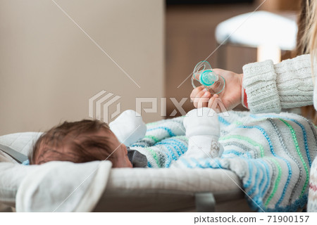 Hand holds a pacifier as a baby item for reassurance 71900157
