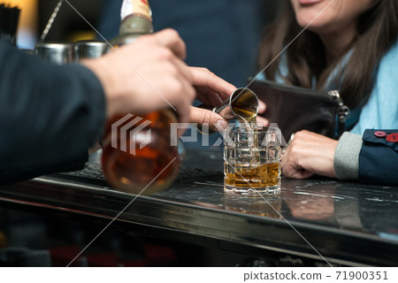 Barman hand pouring strong alcohol into a cocktail glass using a professional bartender tool on 71900351