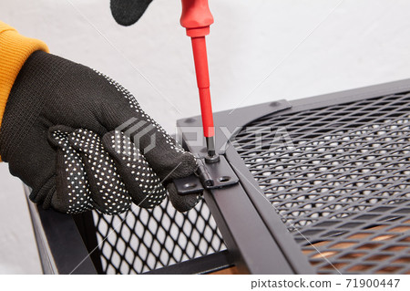 Purchaser tightens screws on doors of metal frame of TV stand using screwdriver. 71900447