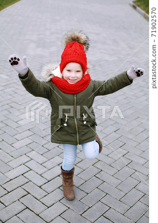 Sweet little funny girl in trendy outfit walking and dancing on the street, having fun, waving hands Sweet little funny girl in trendy outfit walking and dancing on the street, having fun, waving hands 71902570