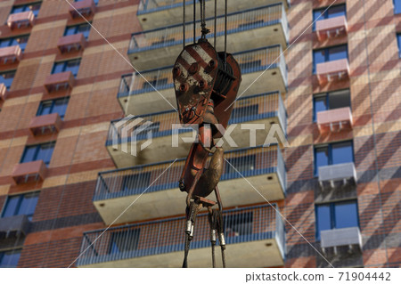 Construction crane hook with multi-storey building under construction (new residential complex) on the background. Construction site upon renovation program in Cheryomushki district, Moscow, Russia 71904442