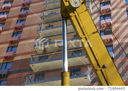 Part of a construction machine (excavator or crane) with multi-storey building under construction (new residential complex) on the background, Moscow, Russia 71904443