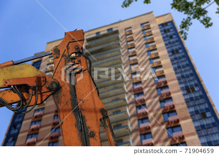 Part of a construction machine  with multi-storey building under construction (new residential complex) on the background. 71904659