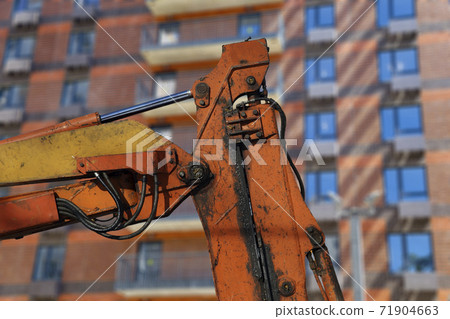 Part of a construction machine  with multi-storey building under construction (new residential complex) on the background. 71904663