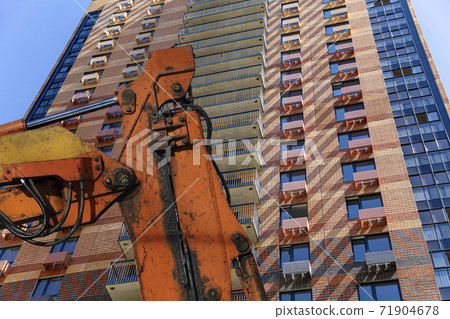 Part of a construction machine  with multi-storey building under construction (new residential complex) on the background. 71904678