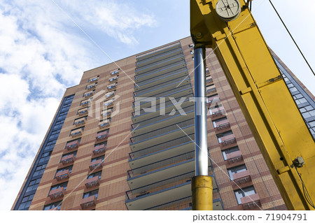 Part of a construction machine (excavator or crane) with multi-storey building under construction (new residential complex) on the background, Moscow, Russia Part of a construction machine (excavator or crane) with multi-storey building under construction (new residential complex) on the background, Moscow, Russia 71904791