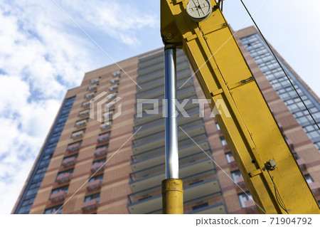 Part of a construction machine (excavator or crane) with multi-storey building under construction (new residential complex) on the background, Moscow, Russia Part of a construction machine (excavator or crane) with multi-storey building under construction (new residential complex) on the background, Moscow, Russia 71904792