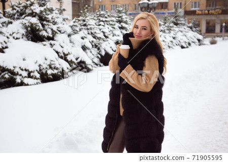 Portrait of european style fashionable woman drinking coffee in winter park. Portrait of european style fashionable woman drinking coffee in winter park. 71905595
