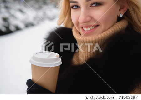 Portrait of european style fashionable woman drinking coffee in winter park. Portrait of european style fashionable woman drinking coffee in winter park. 71905597