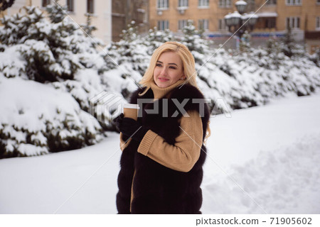 Portrait of european style fashionable woman drinking coffee in winter park. Portrait of european style fashionable woman drinking coffee in winter park. 71905602