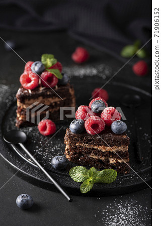 slices of homemade chocolate cake with fresh fruit on a black plate slices of homemade chocolate cake with fresh fruit on a black plate 71906152