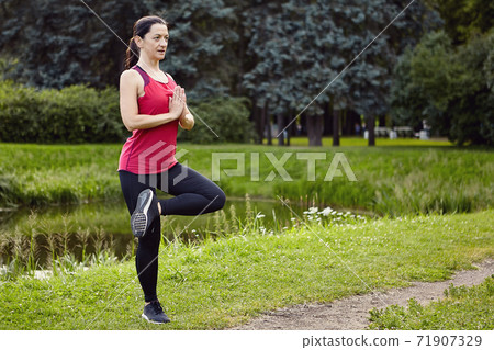 Yoga in public park by white woman. 71907329