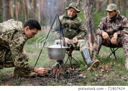 Hunter Sets Fire in Forest Cooking Bonfire Food. 71907424
