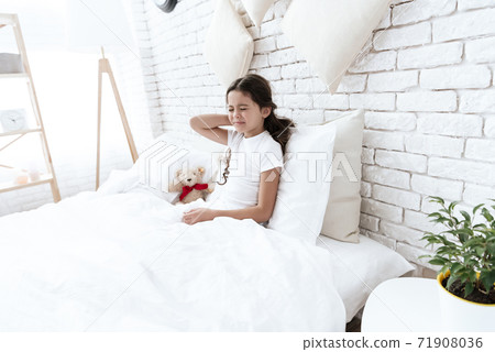 A girl lies on bed and holds neck in sharp pain. A girl lies on bed and holds neck in sharp pain. 71908036