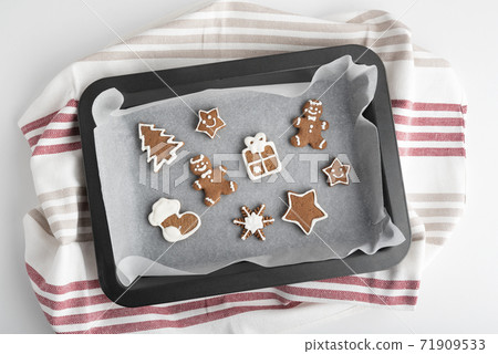 Various Christmas cookies with glazed sugar icing on baking sheet. Traditional baking 71909533