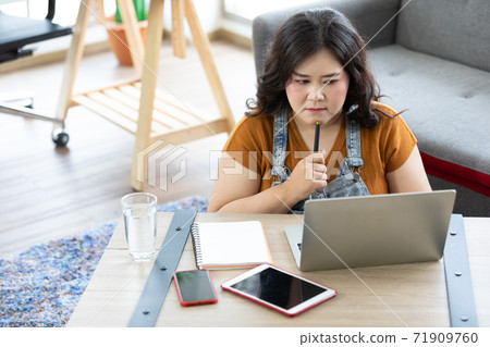 chubby woman looking at laptop computer and thinking about work or study 71909760