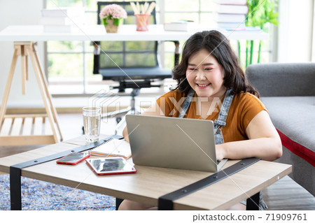 smiling chubby woman works from home and studying with computer laptop 71909761