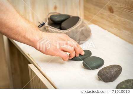 Masseur takes black massage stones Masseur takes black massage stones 71910010