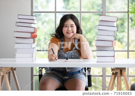 asian chubby woman learning and doing homework at desk with many textbook asian chubby woman learning and doing homework at desk with many textbook 71910083