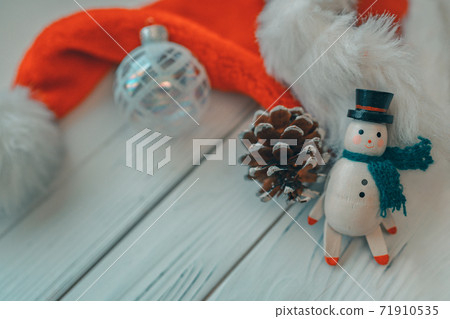 Christmas wooden snowman white wood background with miniature vintage toy, pine cone, glass ball ornament and santa hat for xmas holidays Christmas wooden snowman white wood background with miniature vintage toy, pine cone, glass ball ornament and santa hat for xmas holidays 71910535