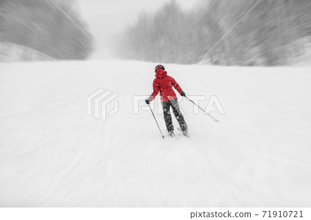 Downhill skiing Alpine ski during snowstorm. Woman athlete riding snowy slope in cold weather whiteout. winter snowsport Downhill skiing Alpine ski during snowstorm. Woman athlete riding snowy slope in cold weather whiteout. winter snowsport 71910721