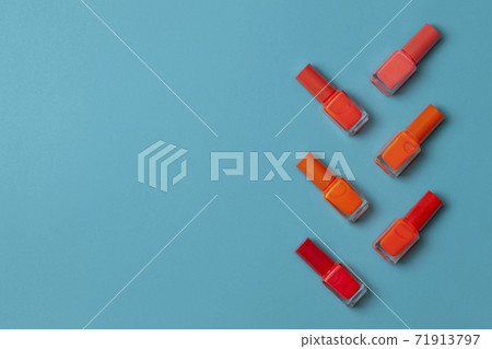 Orange nail polishes bottle on a turquoise paper background Orange nail polishes bottle on a turquoise paper background 71913797
