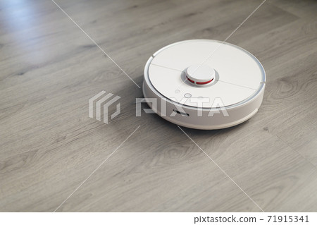 robotic vacuum cleaner on laminate floor in action robotic vacuum cleaner on laminate floor in action 71915341