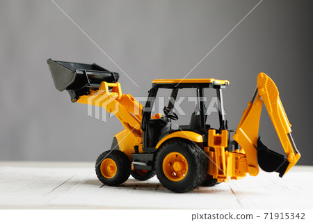 tractor toy on housing construction blueprint, grey background tractor toy on housing construction blueprint, grey background 71915342