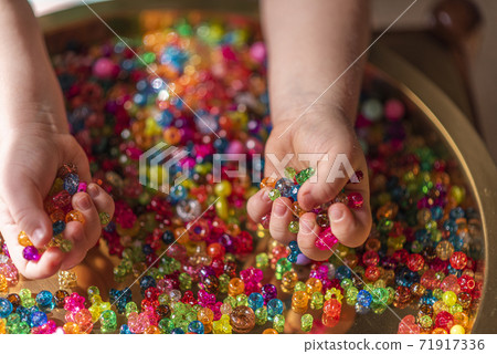 A girl's hand holds colored heart shaped beads A girl's hand holds colored heart shaped beads 71917336