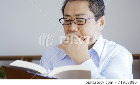 Middle-aged man reading in the living room Middle-aged man reading in the living room 71918880