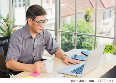 Asian executive senior businessman sitting on desk office with his office Asian executive senior businessman sitting on desk office with his office 71920061