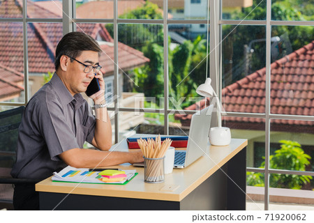 senior businessman sitting on desk office he using his mobile phone 71920062