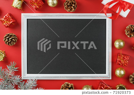 Photo frame with free black space around Christmas decorations and gifts on a red background 71920373