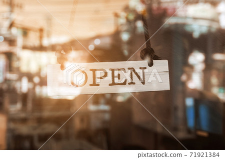 A business sign that says open on cafe or restaurant hang on door at entrance. 71921384
