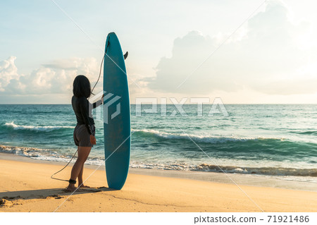 Surfer woman carrying their surfboards on sunset beach with sun light . Surfer woman carrying their surfboards on sunset beach with sun light . 71921486
