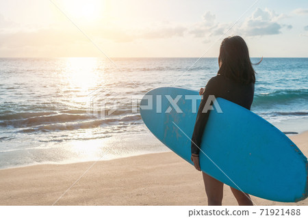 Surfer woman carrying their surfboards on sunset beach with sun light . Surfer woman carrying their surfboards on sunset beach with sun light . 71921488