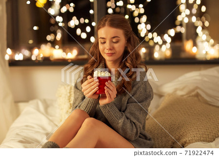 happy woman holding mug with whipped cream in bed happy woman holding mug with whipped cream in bed 71922474